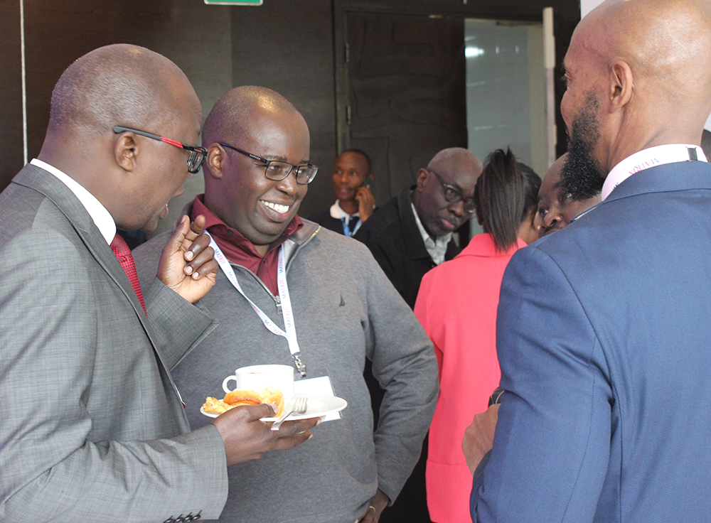 Three people conversing and enjoying tea and snacks